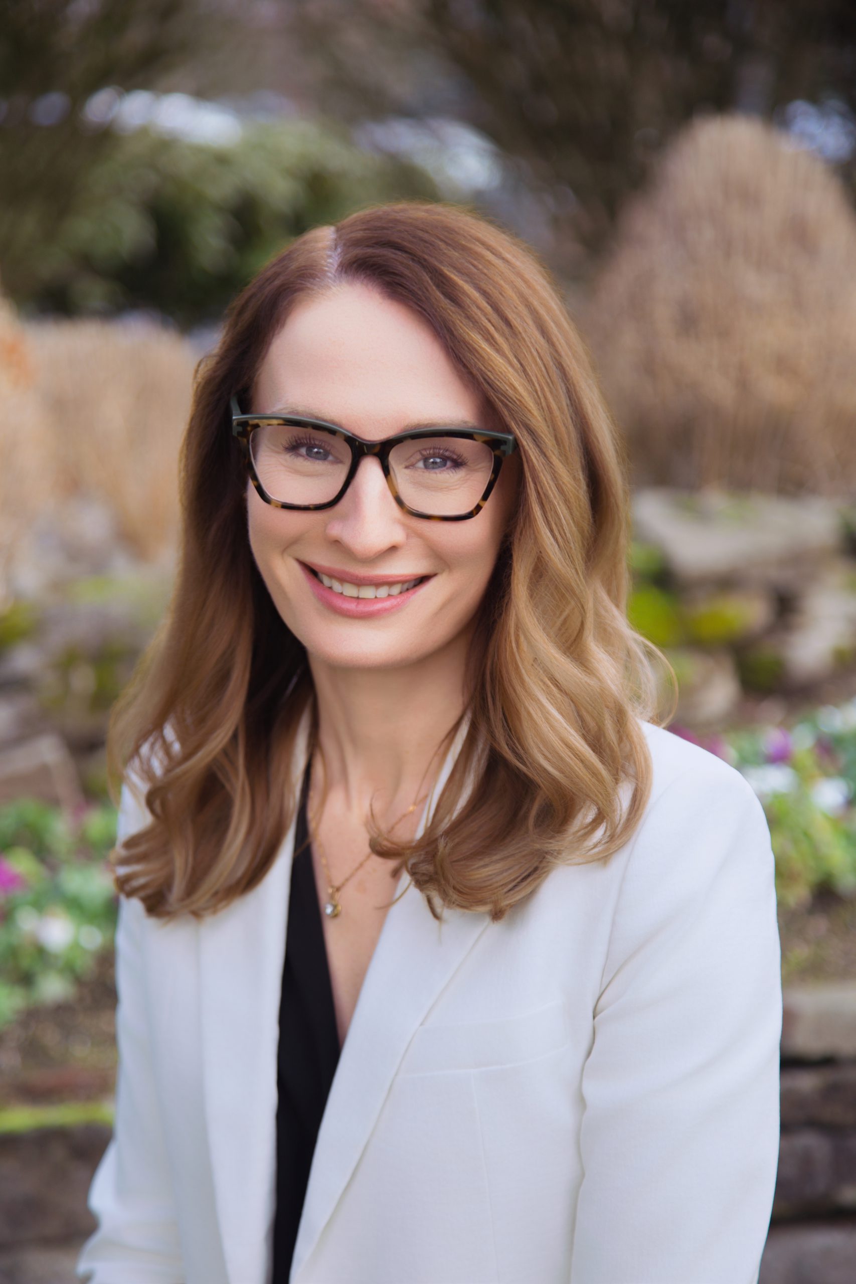 An image of Dr. Hannah Beatty DMD wearing a white blazer over a black top.